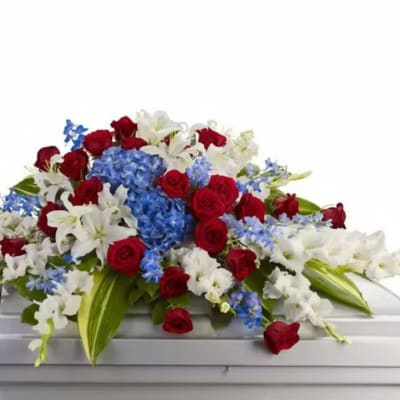 Red roses, white lilies, and blue hydrangeas arranged on a casket