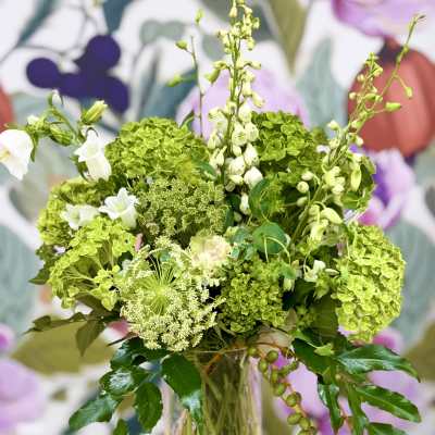 Green and white floral arrangement in a clear glass vase