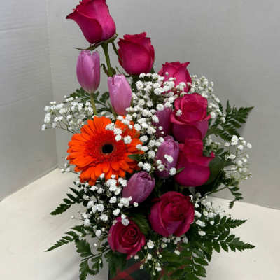 Pink roses and tulips with an orange gerbera daisy in a gift box