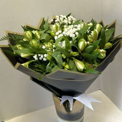 Bouquet of green buds and white filler flowers in a tall vase