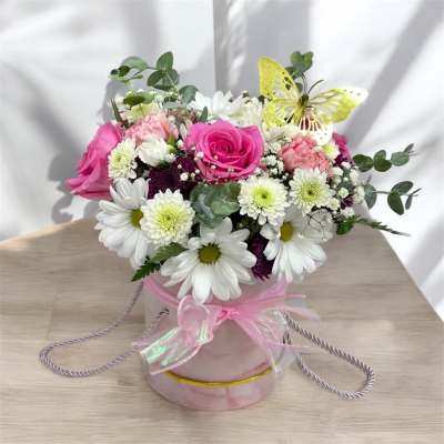 Round pink hatbox arrangement with pink roses, white daisies, and a yellow decorative butterfly.