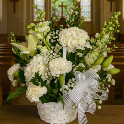 White floral arrangement in a white basket with a striped ribbon