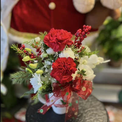 Red and white floral arrangement with a red ribbon in a white vase