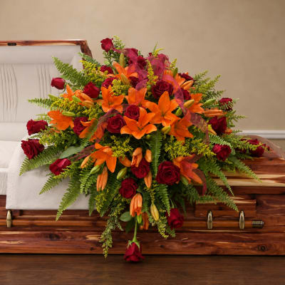 Orange lilies and red roses arranged on a wooden casket