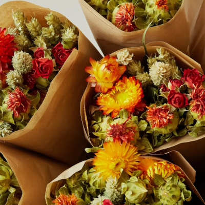 Bouquets of orange and red flowers wrapped in brown paper