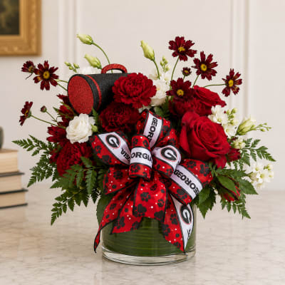 Red and white floral arrangement in a glass vase with a Georgia ribbon