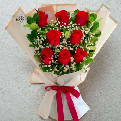 Bouquet of red roses with baby's breath in white wrapping and a red ribbon
