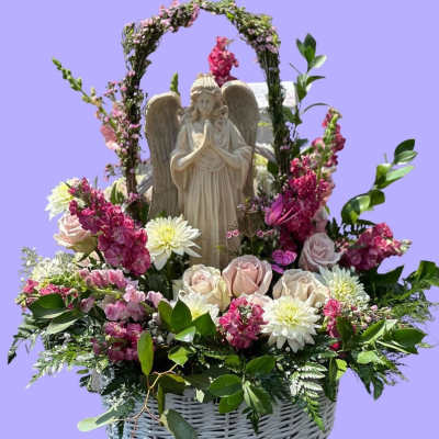 Basket arrangement with an angel statue, pink and white flowers, and greenery