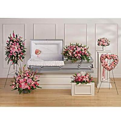 Funeral casket surrounded by pink floral sprays and wreaths