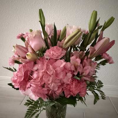 Pink bouquet with hydrangeas, lilies, and carnations in a clear glass vase