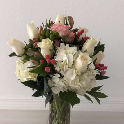 Bouquet of white and pink roses with hydrangeas in a clear glass vase