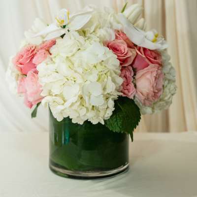Pink roses and white hydrangeas in a green glass vase