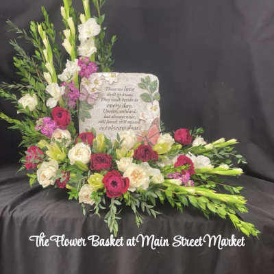 Sympathy floral arrangement with pink and white flowers around a memorial plaque