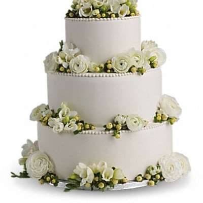 Four-tier white wedding cake with white floral decorations