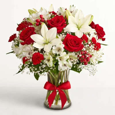 Bouquet of red roses and white lilies in a glass vase with a red ribbon