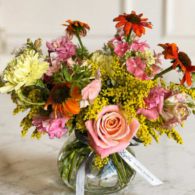 Mixed bouquet in a clear glass vase with pink, yellow, and orange flowers