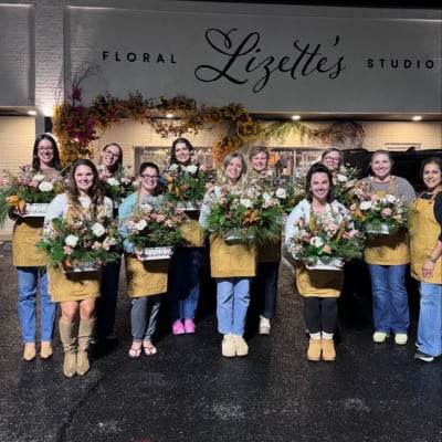 Group of florists holding mixed flower arrangements outside a floral studio