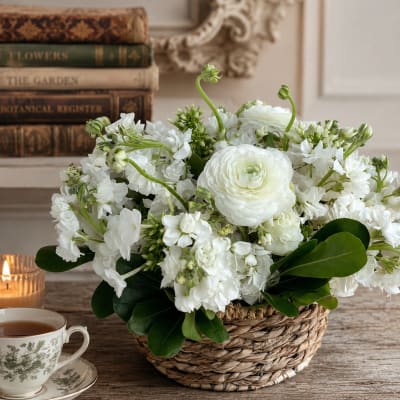 White flowers arranged in a woven basket with glossy green leaves