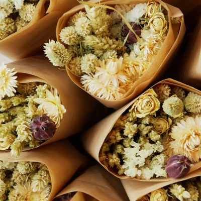 Bouquets of pale yellow and white dried flowers wrapped in brown paper