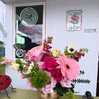 Pink and white floral arrangement in a gold vase on a porch