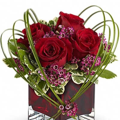 Red roses and pink filler flowers in a square glass vase