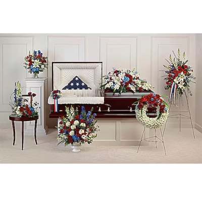 Funeral casket spray and standing floral tributes in red, white, and blue