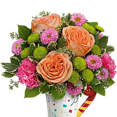 Peach roses and pink pompom flowers in a confetti mug with a party horn