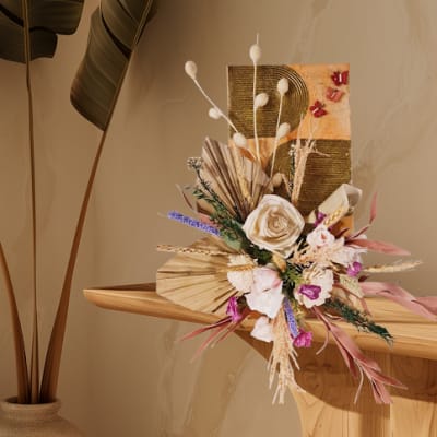 Dried floral arrangement with cream roses and pink accents on a wooden shelf