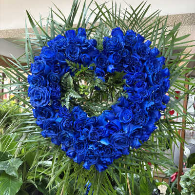 Heart-shaped wreath of vivid blue roses with palm fronds