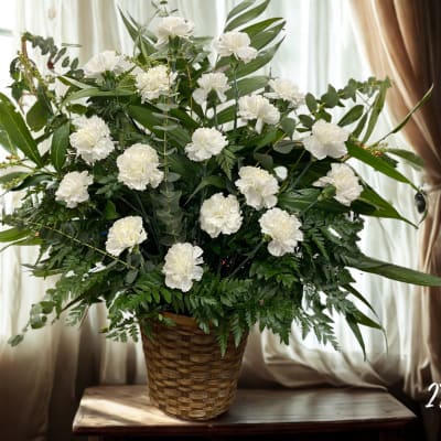 White carnations in a woven basket with mixed greenery