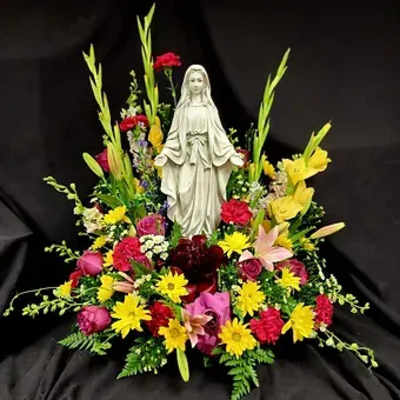 Floral arrangement with a statue of the Virgin Mary in the center