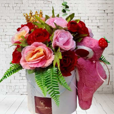 Pink and red rose arrangement in a white box with a pink teddy bear