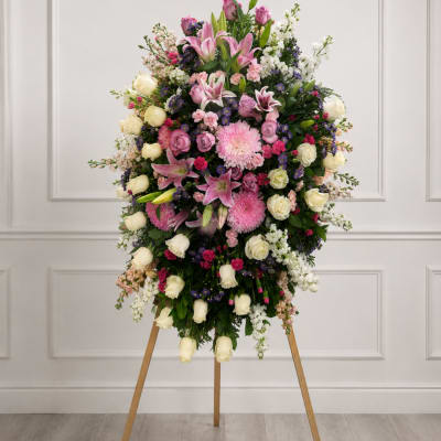 Large standing floral spray with pink, white, and purple flowers on a wooden easel