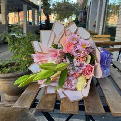 Bouquet of pink and lavender flowers with lily buds wrapped in paper