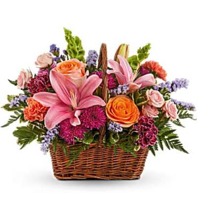 Basket arrangement with pink lilies, orange roses, and purple flowers
