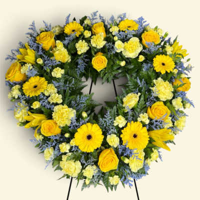 Heart-shaped floral wreath with yellow roses and daisies on a stand