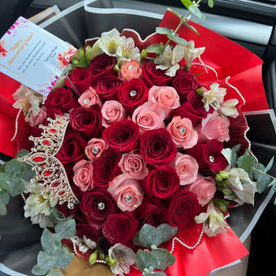 Bouquet of red and pink roses with white alstroemeria and decorative accents