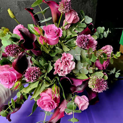 Bouquet of pink roses, calla lilies, and purple blooms with eucalyptus