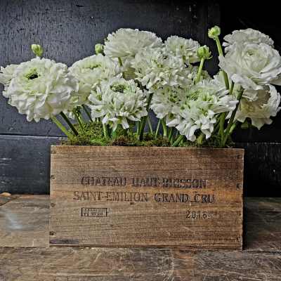 White ranunculus flowers arranged in a wooden crate