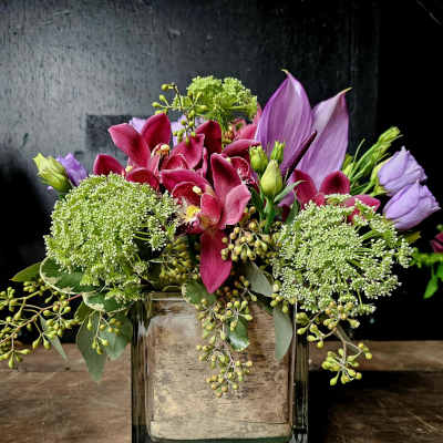 Pink and purple floral arrangement in a square glass vase
