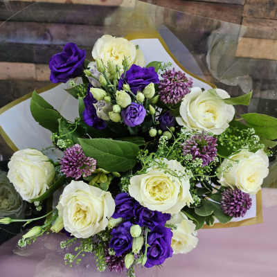 Bouquet of white roses and purple lisianthus wrapped in white paper