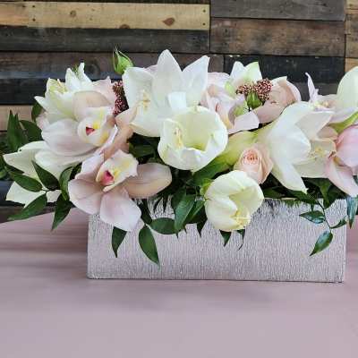 Pastel floral arrangement with white lilies and pale pink orchids in a rectangular container