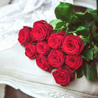 A bouquet of red roses with green leaves on a light upholstered chair