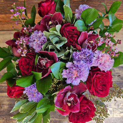 Bouquet of red roses, purple orchids, and lavender carnations