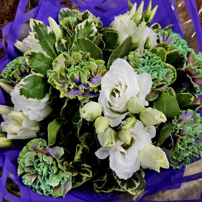 Bouquet of white lisianthus and green-purple carnations wrapped in purple paper