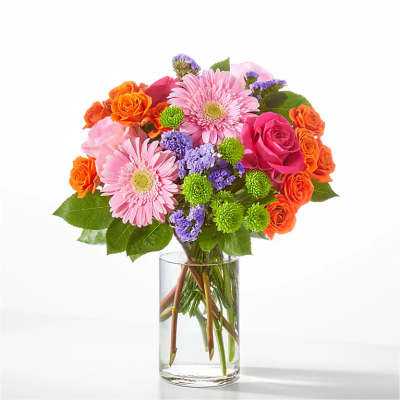 Pink gerbera daisies and orange roses in a clear glass vase