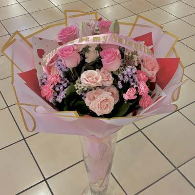 Pink rose bouquet in a clear vase with a Valentine ribbon
