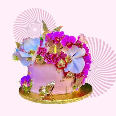 Pink cake decorated with purple and white flowers and gold butterflies
