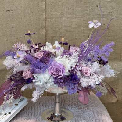 Lavender and white floral arrangement in a silver pedestal vase