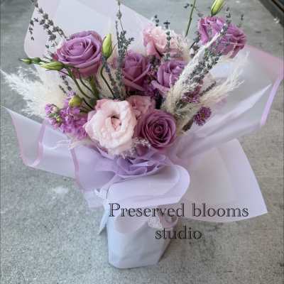 Lavender and pink bouquet of roses and lisianthus wrapped in pale paper